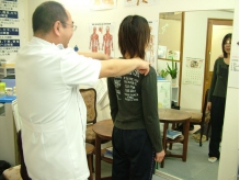 整体の施術前に、立った姿勢で肩まわりを確認する院長